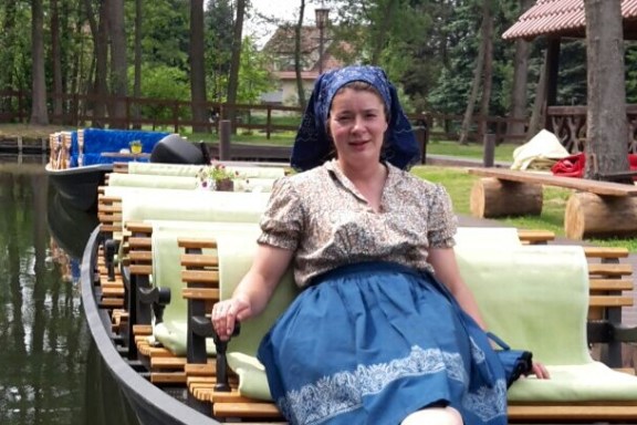 Fährfrau sitzend in Tracht in der vorderen Reihe auf Ihrem Kahn