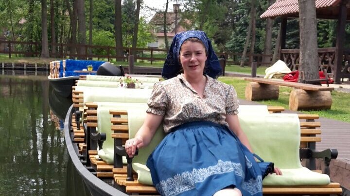 Fährfrau sitzend in Tracht in der vorderen Reihe auf Ihrem Kahn