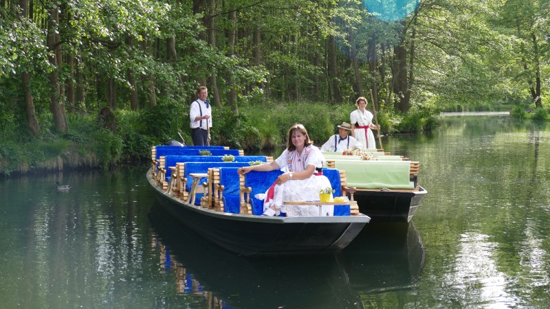 Fährfrau Yvonne und ein Mann auf Ihrem Kahn und ein anderer Kahn neben dran mit einer Frau und einem Mann in Tracht